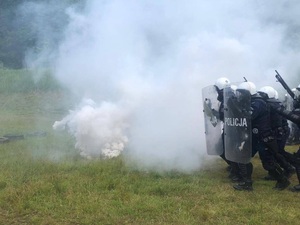 policjanci w tyralierze z tarczami przed nimi dym