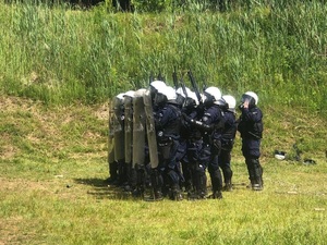 policyjna drużyna z tarczami i strzelbami w szyku bojowym