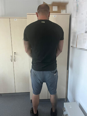 zatrzymany stojący tyłem w biurze komendy  z kajdankami na ręce założone z przodu