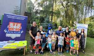 pamiątkowa fotografia uczestników pikniku z policjantami, maskotkami policyjnymi przy stanowisku prfilaktycznym.