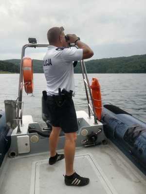 policjant w łodzi patrzy przez lornetkę