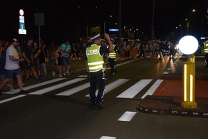Policjant z ruchu drogowego kieruje ruchem pieszych w trakcie rozejścia się kibiców.