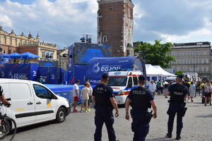 Trzech umundurowanych policjantów obserwujących obiekt sportowy na krakowskim Rynku Głównym