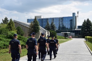 umundurowani policjanci idący w kierunku budynku Akademii Wychowania Fizycznego w Krakowie