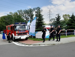 policjanci patrolują pieszo strefę kibica w Rabie Wyżnej, po lewej strnie stoi wóz strażacki