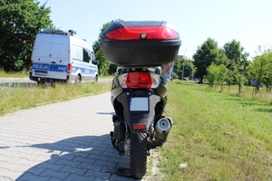 skuter stojący na chodniku w tle radiowóz i osiedle