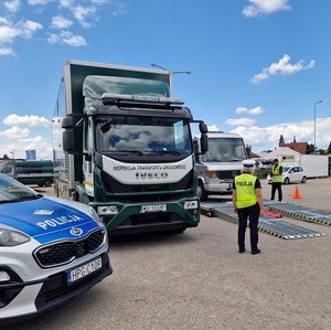 policjantka i inspektor itd prowadzą kontrolę busa z wykorzystaniem mobilnej jednostki diagnostycznej z lewej strony stoi zaparkowany radiowóz