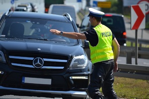 Ppolicjant zatrzymujący do kontroli, wskazujący ręką miejsce do zatrzymania