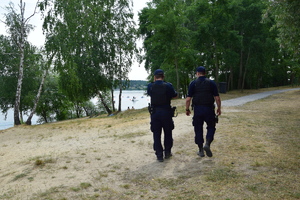 dwóch patrolujących na plaży policjantów, widoczni tyłem do zdjecia