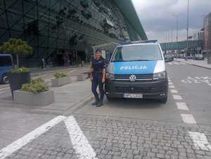 policjantka stojąca przy radiowozie na terenie lotniska