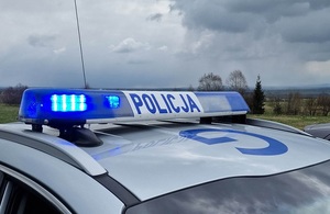 napis policja na dachu radiowozu a z lewej strony niebieski sygnał błyskowy