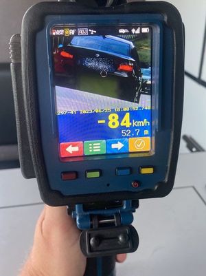 Zdjęcie ekranu miernika prędkości, na którym widoczny jest zarejestrowany samochód audi oraz jego prędkość -84 kilometry na godzinę (odjazd od miejsca kontroli)