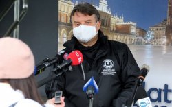 Jarosław Foremny mówi do mikrofonu, w tle rollup sanepidu
