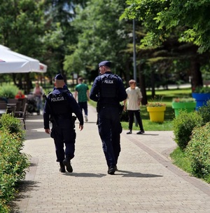 policjanci pieszo patrolują teren parku miejskiego