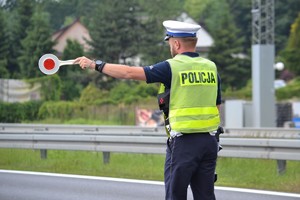 Policjant ruchu drogowego zatrzymujący tarczą pojazd do kontroli
