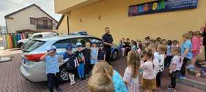 Policjant podczas pokazu radiowozu policyjnego wraz z grupą przedszkolaków — kopia