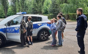 dzieci oglądające policyjny radiowóz w obecności umundurowanego policjanta