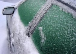 Oszronione szyby i samochód pokryty śniegiem