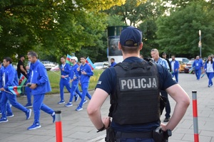 umundurowany policjant obserwujący przejście zawodników na stadion przy ul. Reymonta