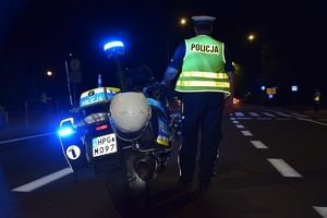 umundurowany policjant ruchu drogowego stojący tyłem do zdjęcia przy motocyklu obserwujący rejon przy stadionie na ul. Reymonta