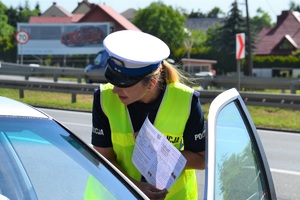 Policjantka ruchu drogowego wręcza kierującemu  ulotkę dotyczącą wyprzedzania