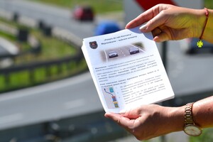 Zbliżenie na dłonie trzymające ulotkę o wyprzedzaniu. W tle perpektywa drogi