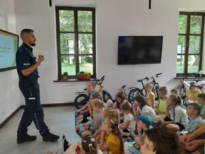 Umundurowany policjant oraz dzieci biorące udzial w spotkaniu profilaktycznym