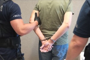 zatrzymany w kajdankach obok dwóch policjantów