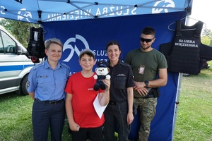 chłopiec trzymający maskotkę słuby więziennej z funkcjonariuszkami i funkcjonariuszem służby więziennej