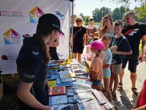 dzieci gromadza sie przy policyjnym stanowisku. Na stole kolorowe ulotki i broszury
