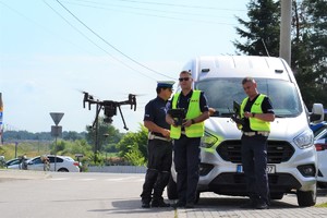 Dwóch policjantów operujących dronem, dron i policjant ruchu drogowego.