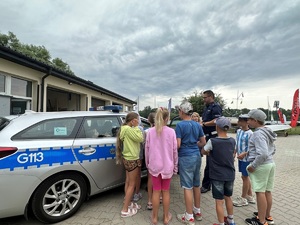 Dzieci w obecności policjanta oglądają radiowóz