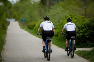 Dwóch policjantów jedzie na rowerach ścieżką pieszo-rowerową.