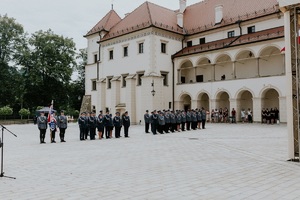 poczet sztandarowy i policjanci stojący w szeregach ia w tle piękny suski zamek