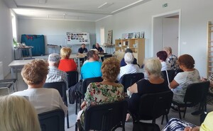 dwóch policjantów prowadzących prelekcje, przed nimi, a tyłem do zdjęcia siedzący sieniorzy