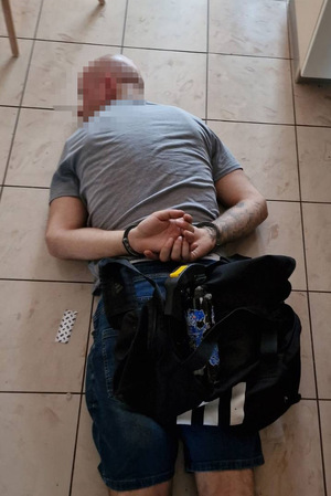 zatrzymany mężczyzna leżący na ziemi. Na rękach założone kajdanki