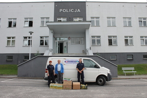 policjanci wraz z zebranymi darami na tle samochodu biorącego udział w konwoju humanitarnym