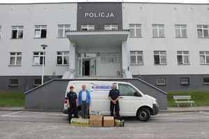 policjanci wraz z zebranymi darami na tle samochodu biorącego udział w konwoju humanitarnym