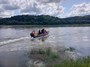 Policjant oraz strażacy płyną łodzią po rzece Dunajec