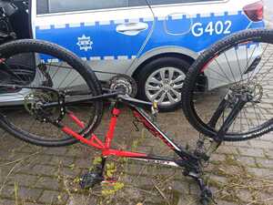 KPP Oświęcim. Obok radiowozu stoi rower odwrócony  kołami do góry numery fabryczne na dolnej części ramy roweru