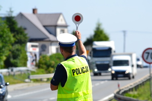 Policjant ruchu drogowego zatrzymuje pojazd do kontroli drogowej przy użyciu tarczy do zatrzymywania pojazdów