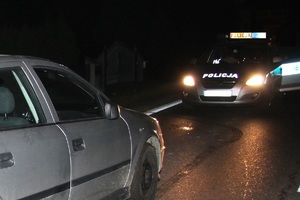 Nocna Kontrola drogowa radiowóz stoi na ulicy z włączonymi światłami przed nim samochód osobowy