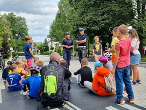 policjantka i policjant omawiają z dziećmi zasady ruchu drogowego