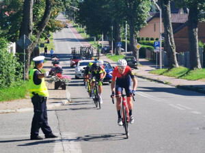 Policjant  ruchu drogowego w żółtej kamizelce wskazuje trasę uczestnikom wyścigu