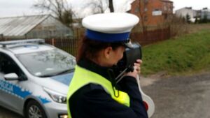 Policjantka mierzy prędkość pojazdów przy użycia ręcznego miernika prędkości