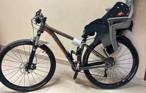 zabezpieczony rower w kolorze czarnym z czerwonymi napisami stojący oparty o ścianę