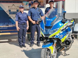 policjanci przy motocyklu policyjnym; w tle stoisko z ulotkami na festynie