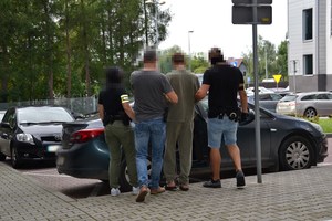 zatrzymany przy radiowozie prowadzony przez nieumundurowanych policjantów