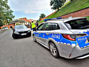 umundurowany policjant zmierzający w kierunku kierowcy czarnego pojazdu osobowego znjadującego sie w rejonie Wawelu. Na pierwszym plaznie widać policyjny radiowóz