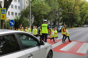 Policjant przeprowadza dzieci przez drogę